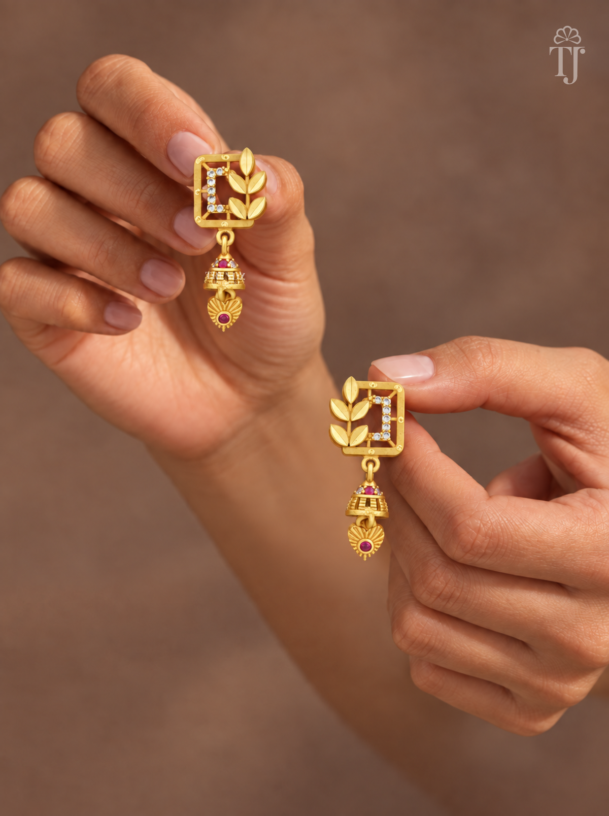 Fingers holding gold plated square leaf earrings with mini jhumka