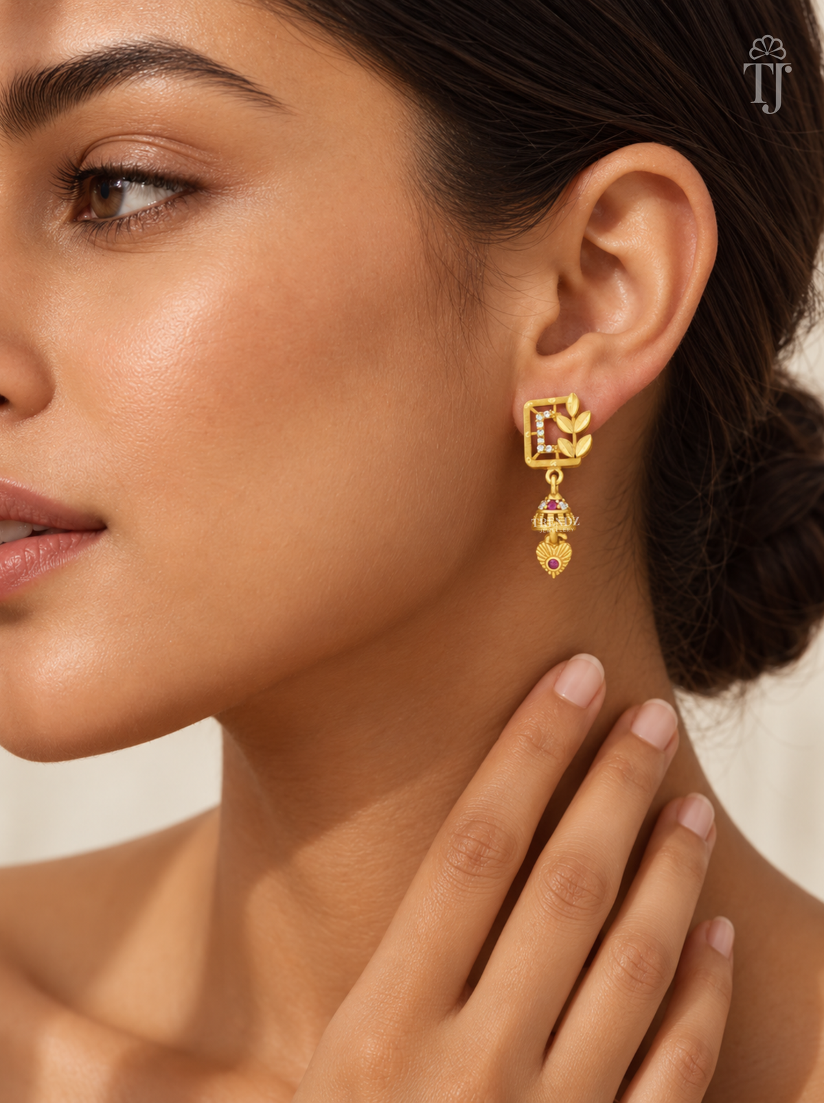 Woman wearing small gold plated square jhumka earrings with leaf branch