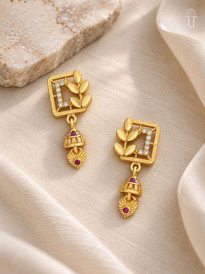 Pair of gold plated square leaf earrings with pink stone jhumka on cream linen