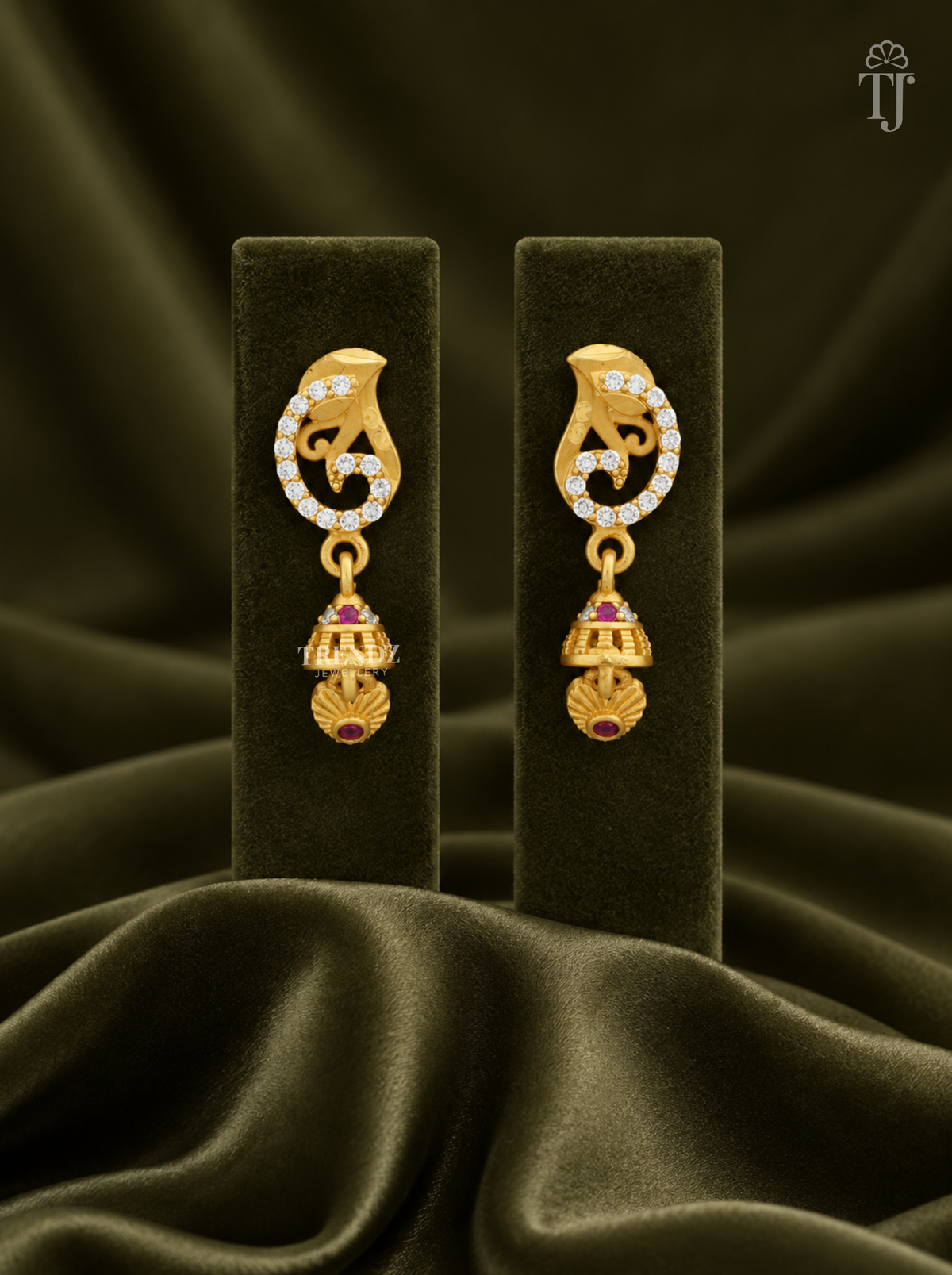 Gold plated swirl jhumka earrings with AD stones on olive green velvet display stand