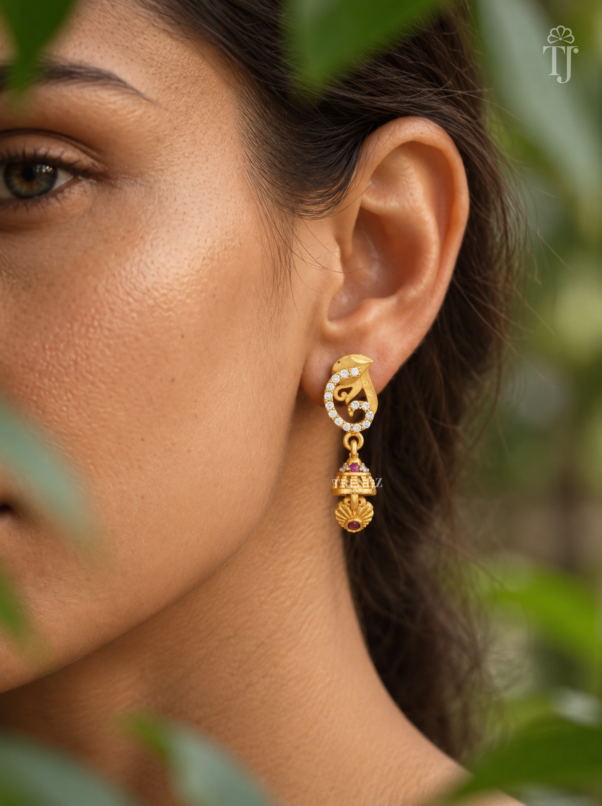 Side view of woman wearing gold plated swirl jhumka drop earrings
