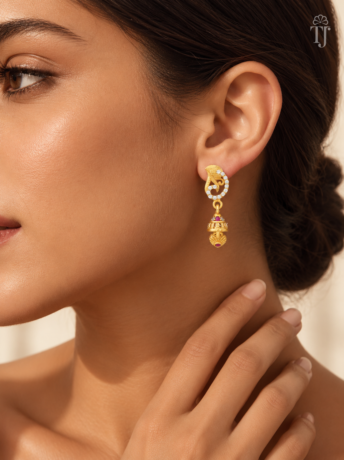 Woman wearing small gold plated swirl design jhumka earrings with AD stones