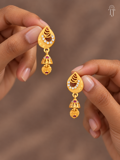 Fingers holding gold plated teardrop earrings with pink stone mini jhumka