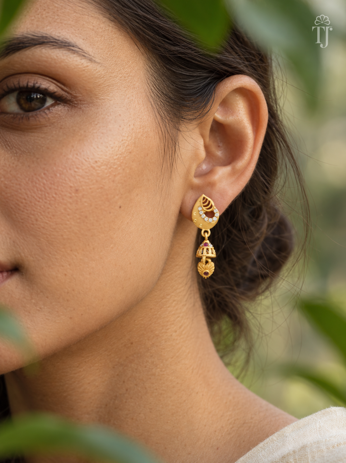 Side view of woman wearing gold plated teardrop jhumka drop earrings