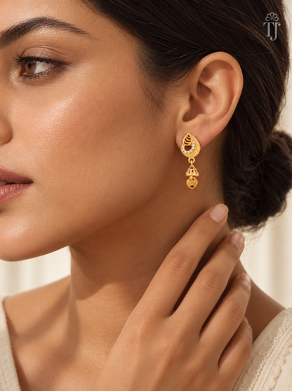 Woman wearing small gold plated teardrop jhumka earrings with AD stones