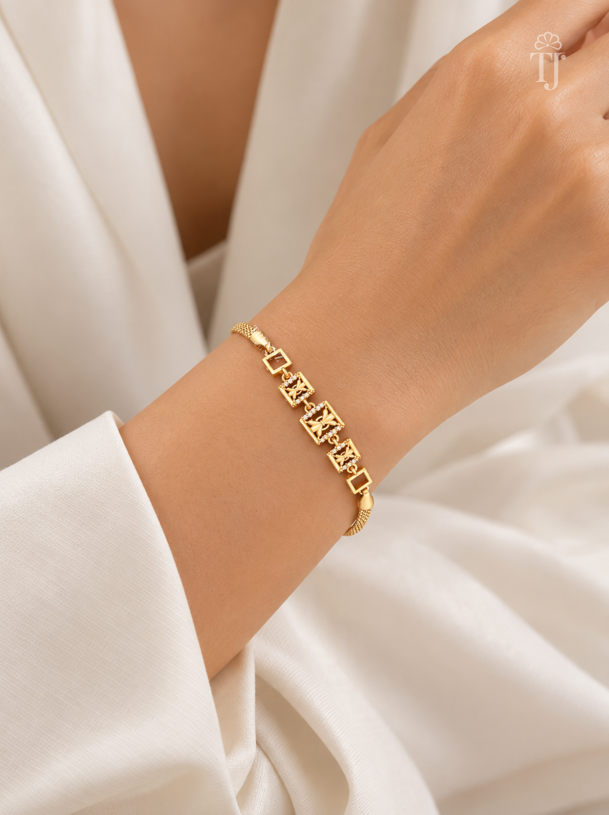 Model wearing designer gold plated hand bracelet on white outfit