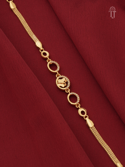 A gold-plated bracelet with a mesh chain, circular links, and a central elephant motif charm, displayed on a deep red fabric background.