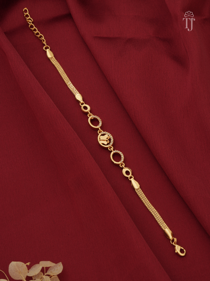 A gold-plated chain bracelet with circular and textured links, displayed diagonally on a draped dark red fabric background.