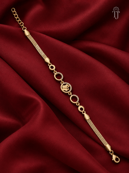 A gold-toned chain bracelet with a textured mesh section, circular links, and a central oval charm, displayed on draped deep red satin fabric.