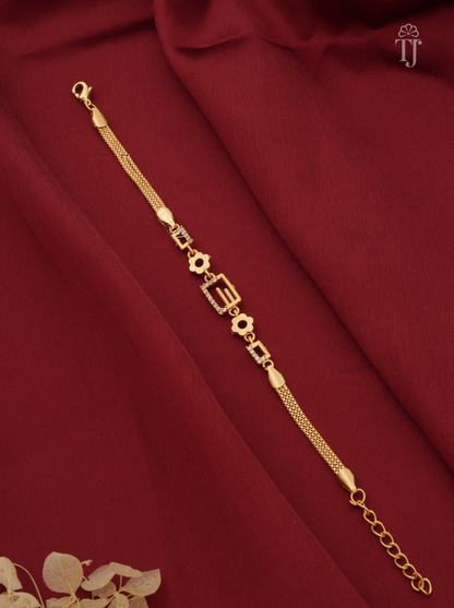 A gold-plated chain bracelet with decorative geometric and floral motifs, displayed diagonally on a draped dark red fabric background.