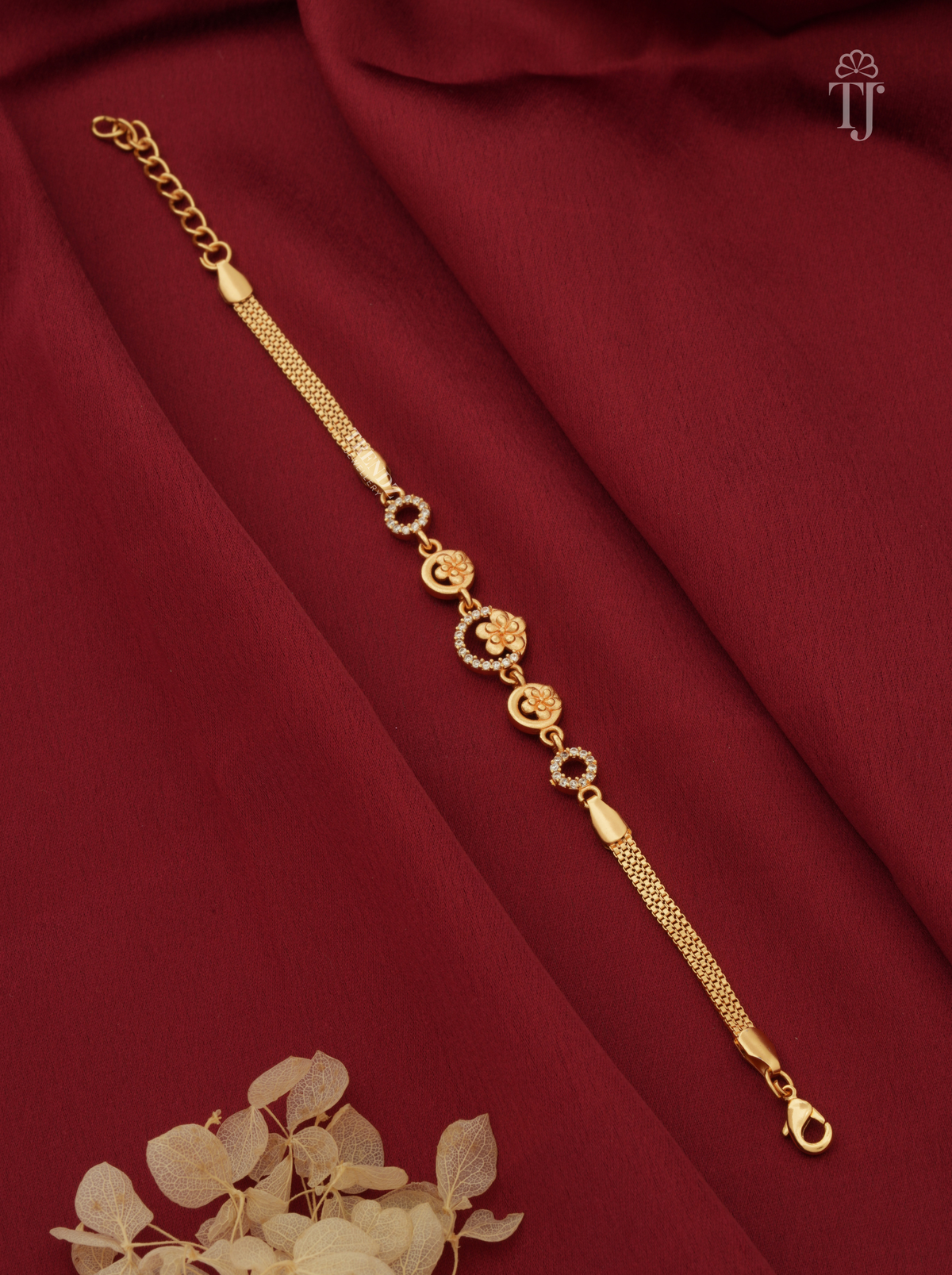 Gold plated floral round bracelet for women on red fabric background