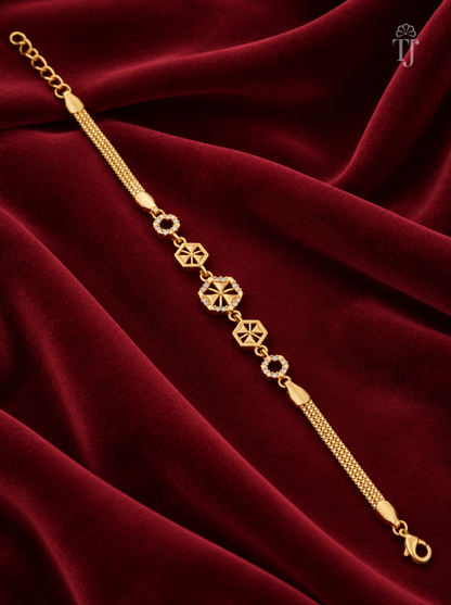 A gold-plated bracelet with geometric and floral motifs, displayed diagonally on a draped deep red velvet fabric background.