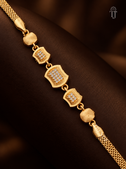 Close up of rectangle gold plated bracelet with AD diamond cushion stations on black fabric