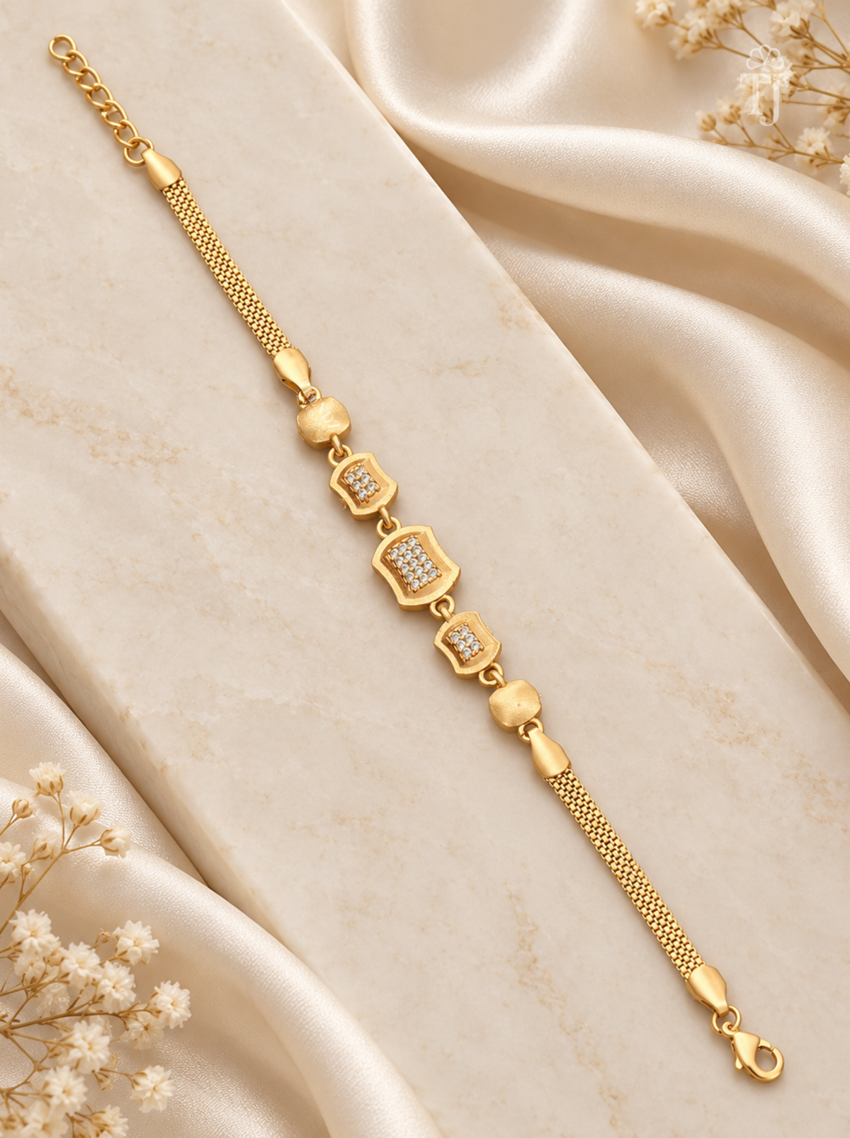 Modern geometric rectangle gold plated bracelet flat lay on cream silk