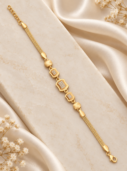 Modern geometric rectangle gold plated bracelet flat lay on cream silk